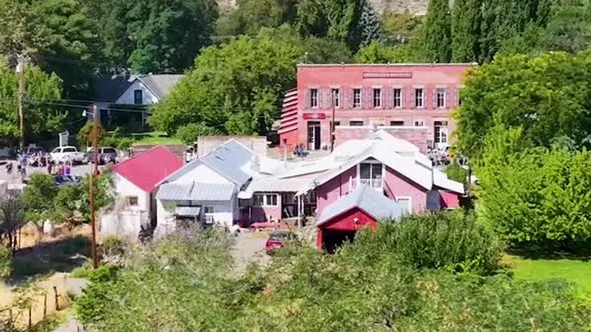 Cedarville rooftops and leafy trees sit beneath a rocky hillside.