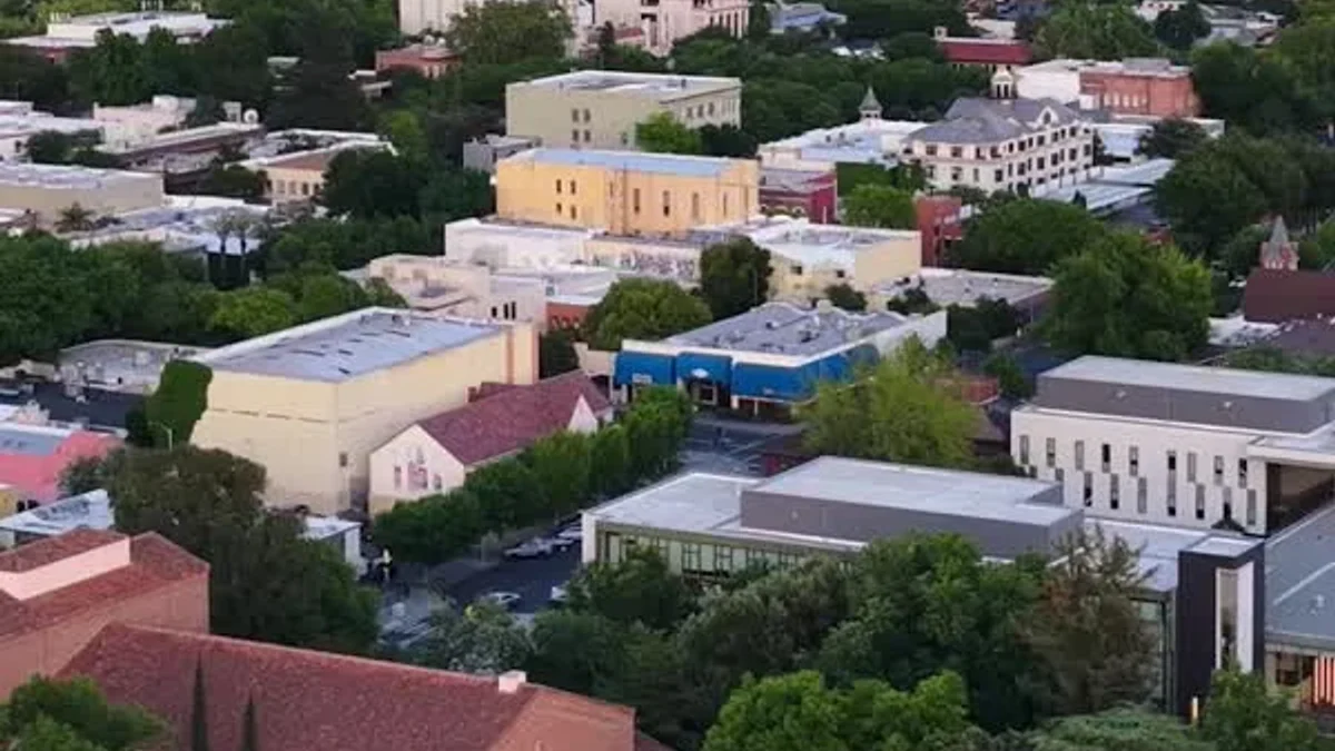 An aerial view looks across leafy Chico streets and downtown buildings at dusk.