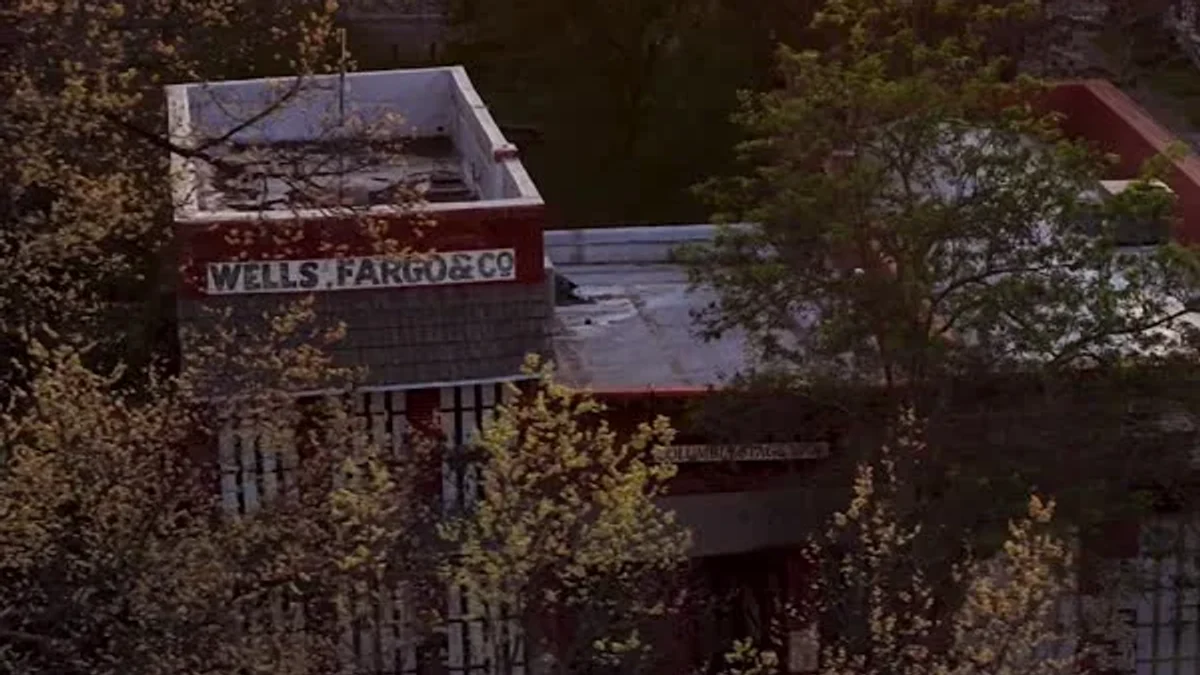 Low sunlight falls across Columbia’s wooden buildings and surrounding trees.
