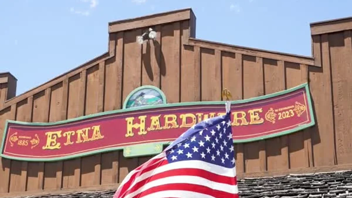 An American flag hangs outside the brick Etna Hardware storefront.
