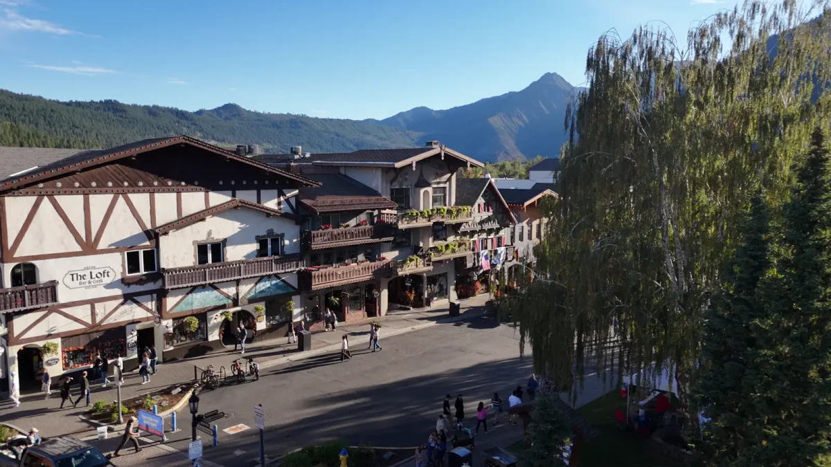 People walk along Leavenworth’s timbered Front Street beneath a mountain skyline.
