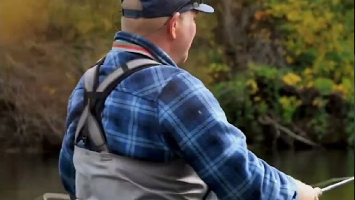 A fly fisher stands in a tree-lined river near Lewiston.