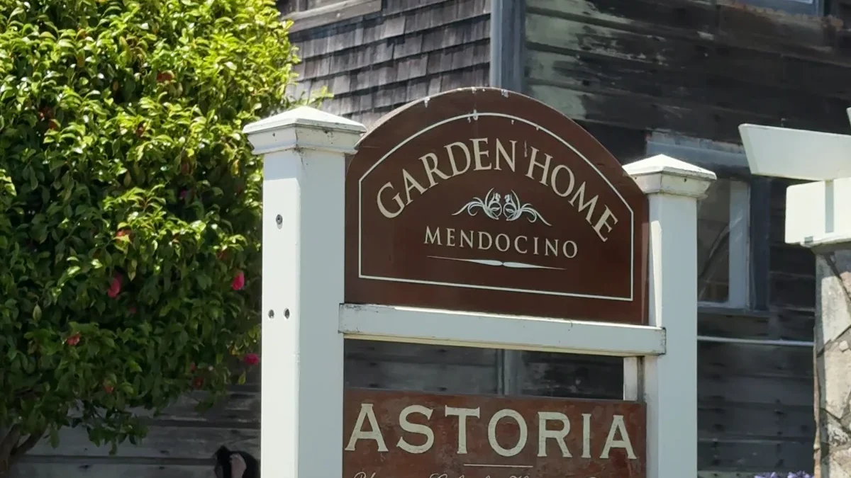 A locally owned Mendocino shop sits among weathered shingles, flowers and a white picket fence.