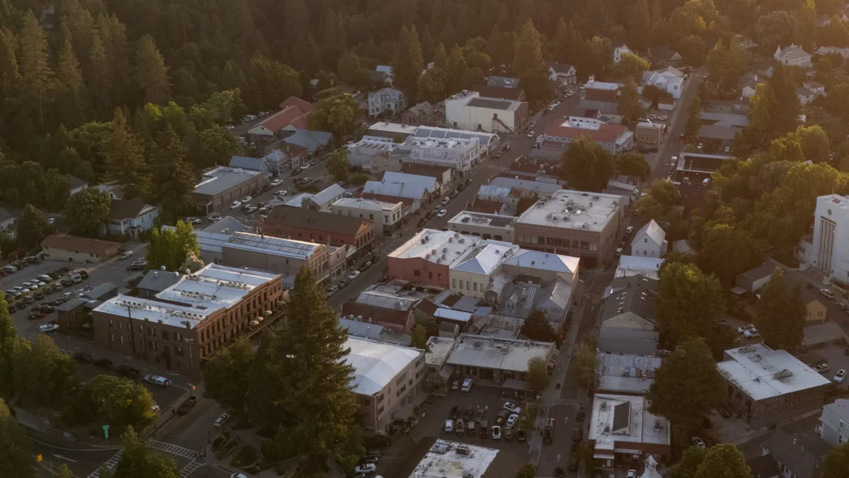 Nevada City rooftops among forested foothills at sunset
