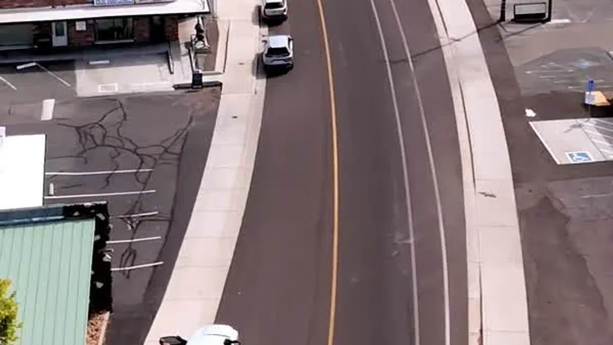 An aerial view follows a broad road past Shasta Lake storefronts and trees.