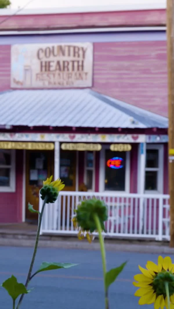 Flowers grow outside the Country Hearth storefront and porch.