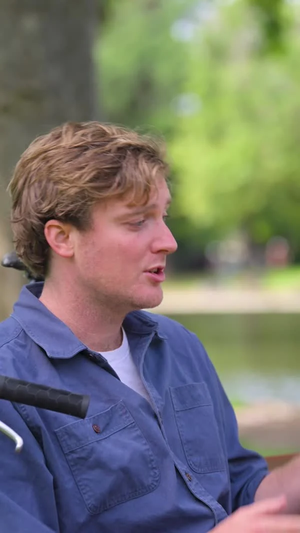 A participant in a blue shirt speaks beside a pond.