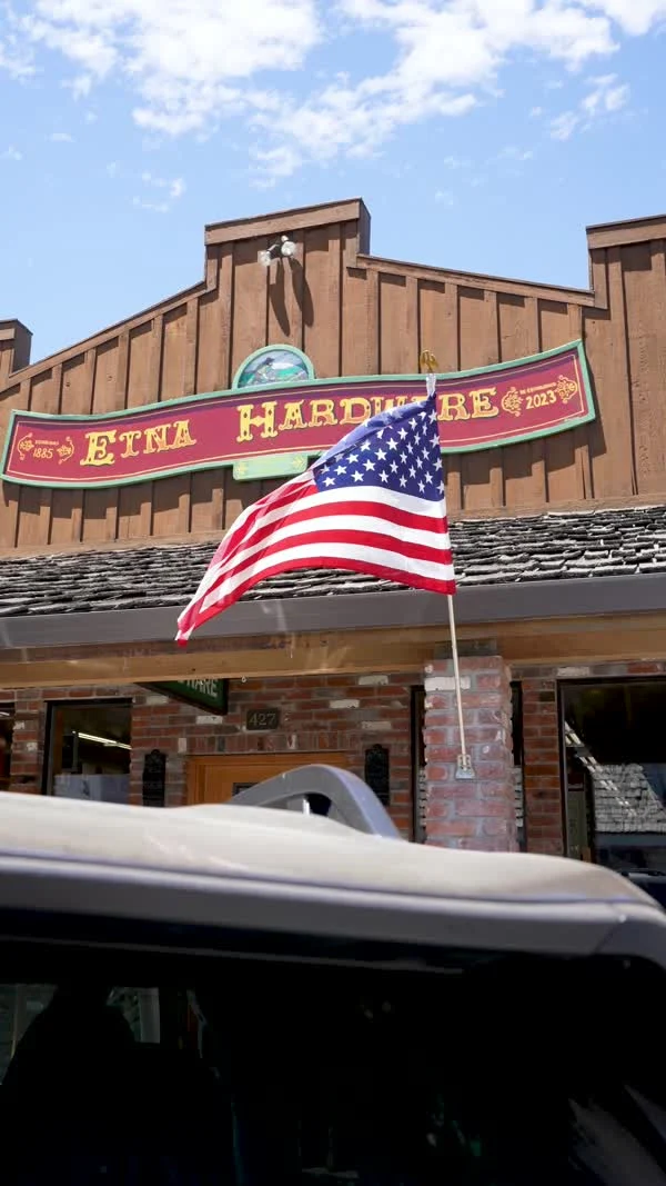 An American flag hangs outside the brick Etna Hardware storefront.