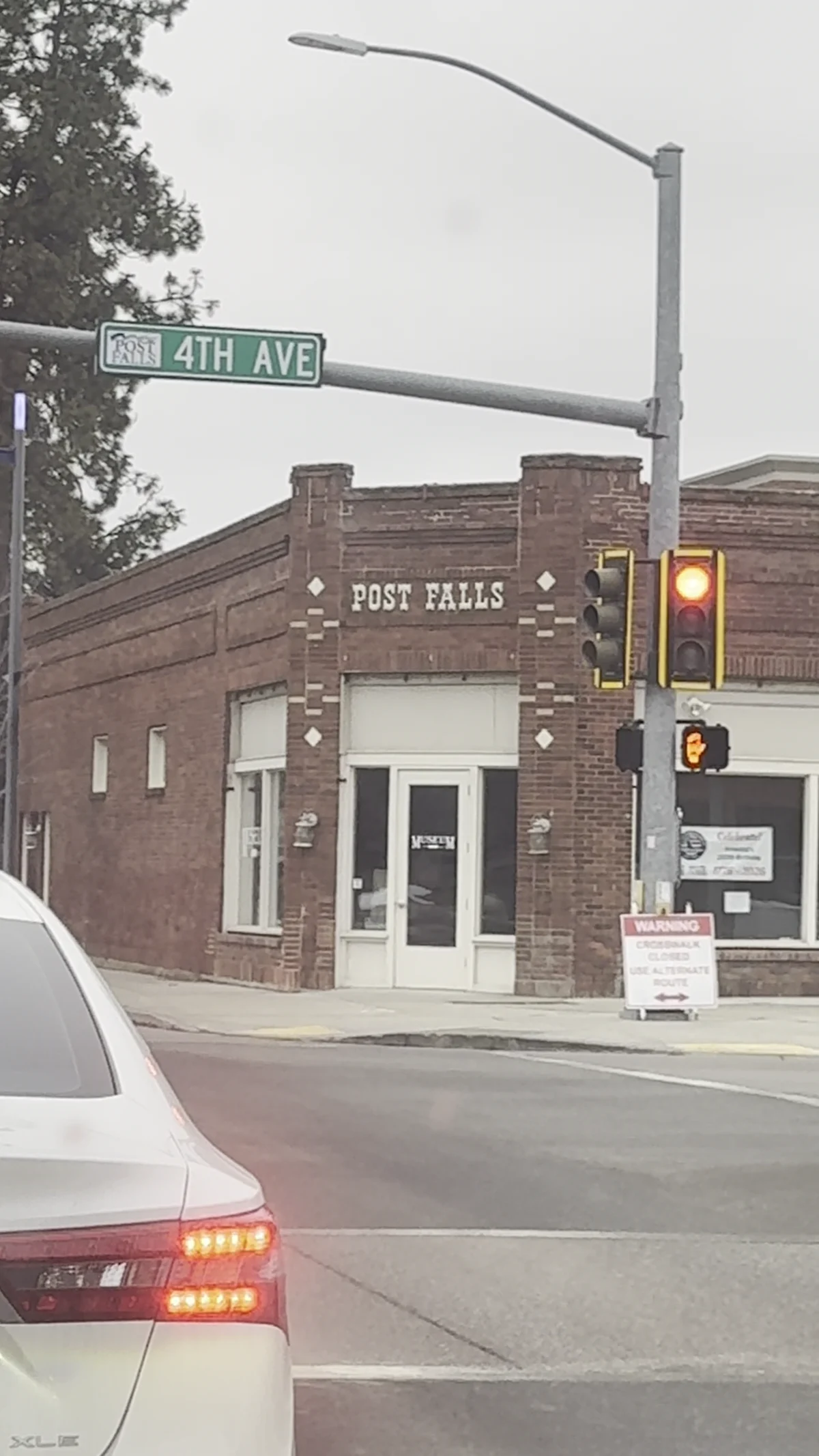 Brick Post Falls museum building beneath Fourth Avenue street sign