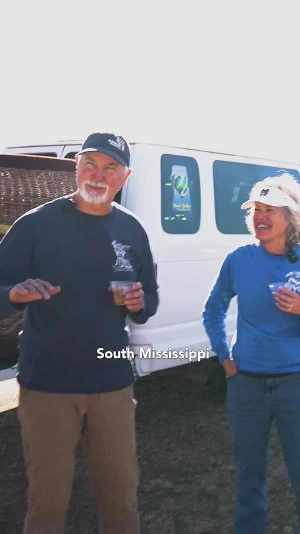 Two interview participants stand beside a van and balloon basket at the festival.