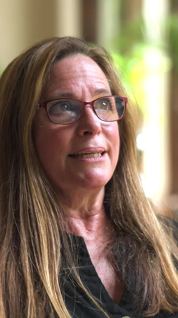 A participant wearing red glasses speaks beside a window in the Oroville film.