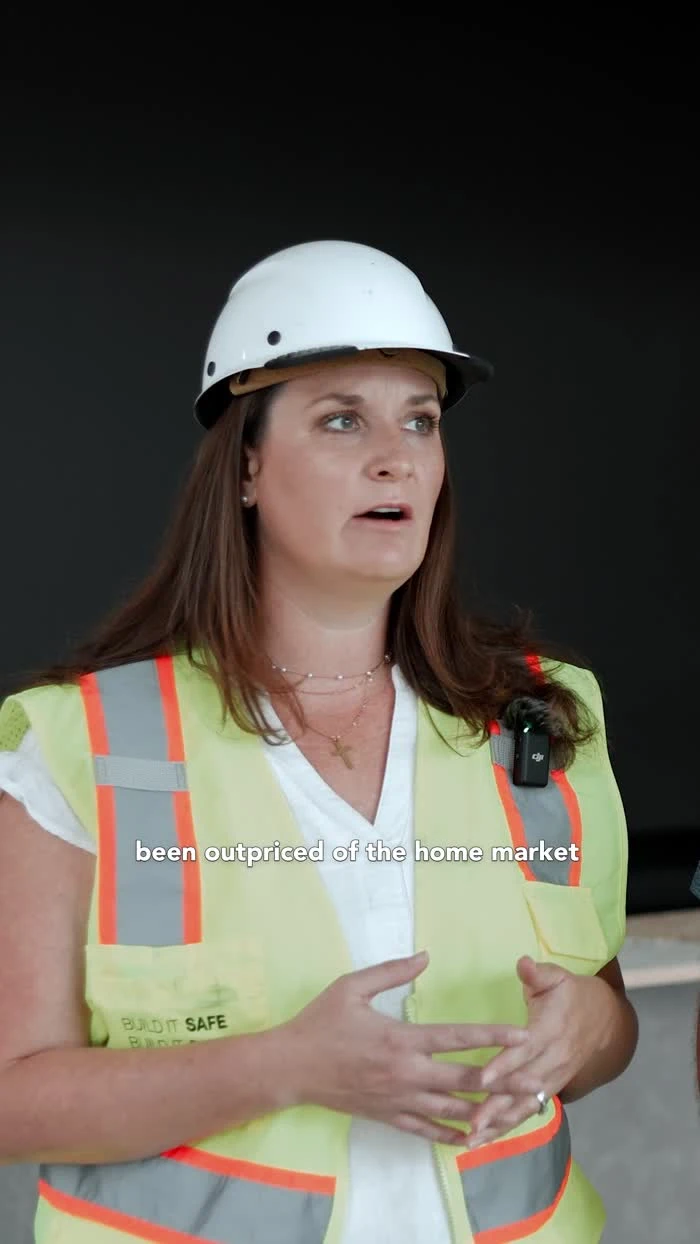 A participant wearing a white hard hat and reflective vest speaks during an interview.