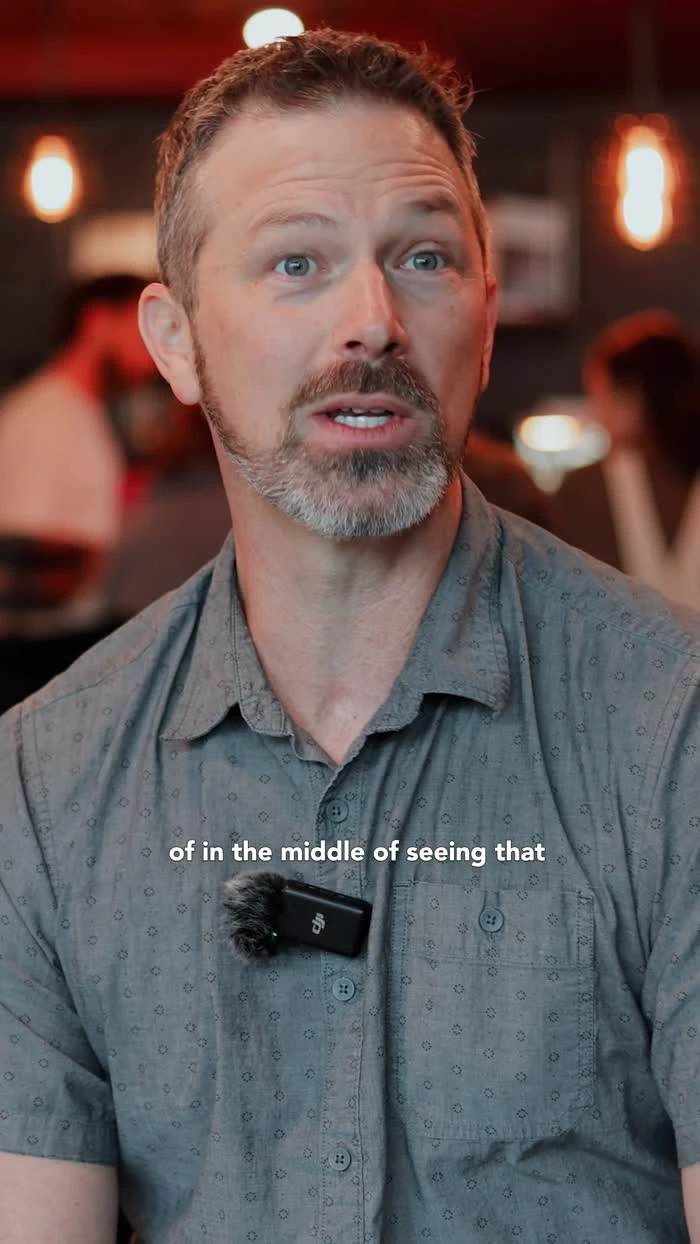 A participant wearing a gray shirt speaks during an indoor interview.