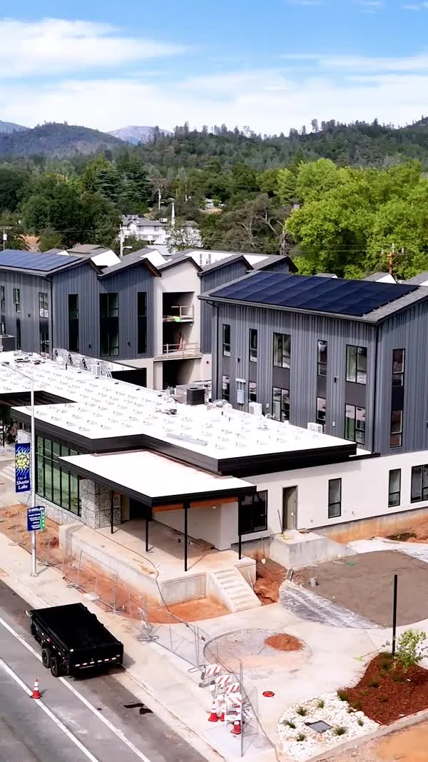 A newly built multi-story building and outdoor terrace stand beside a street.