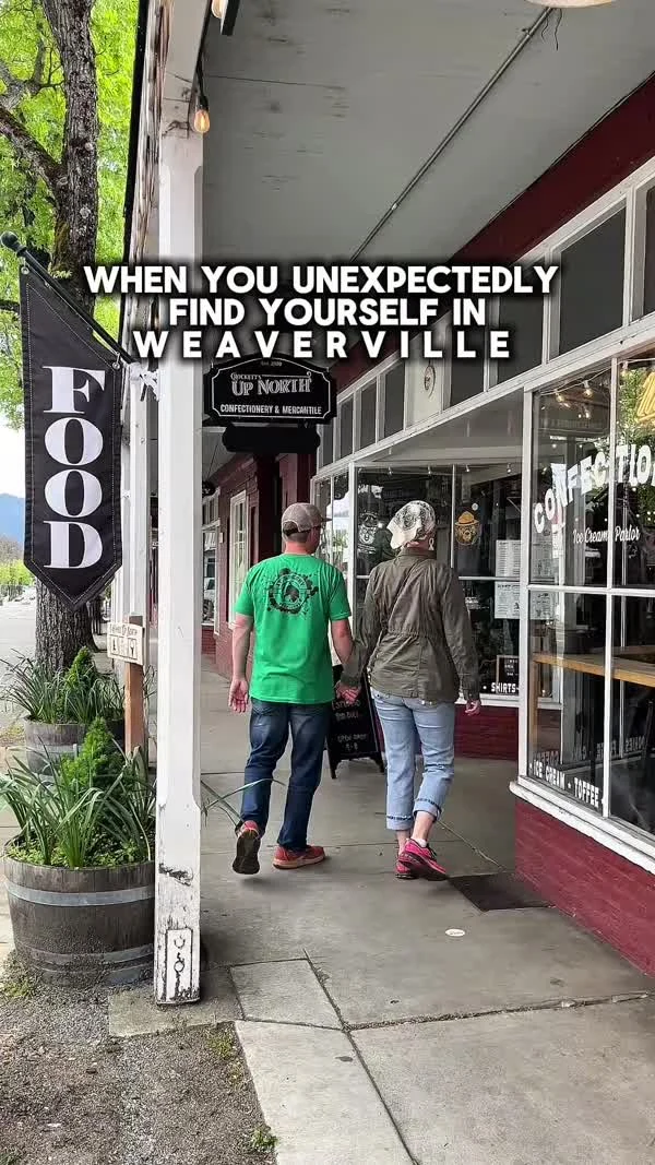Two people walk under a covered downtown sidewalk past a food sign.