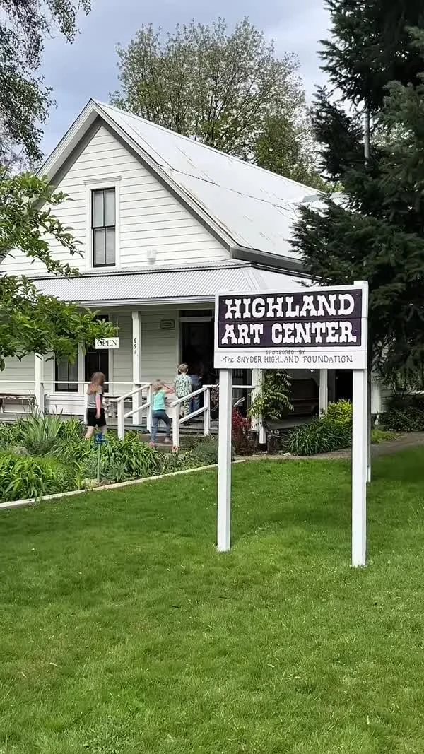 A Highland Art Center sign stands in a lawn in front of a white building.